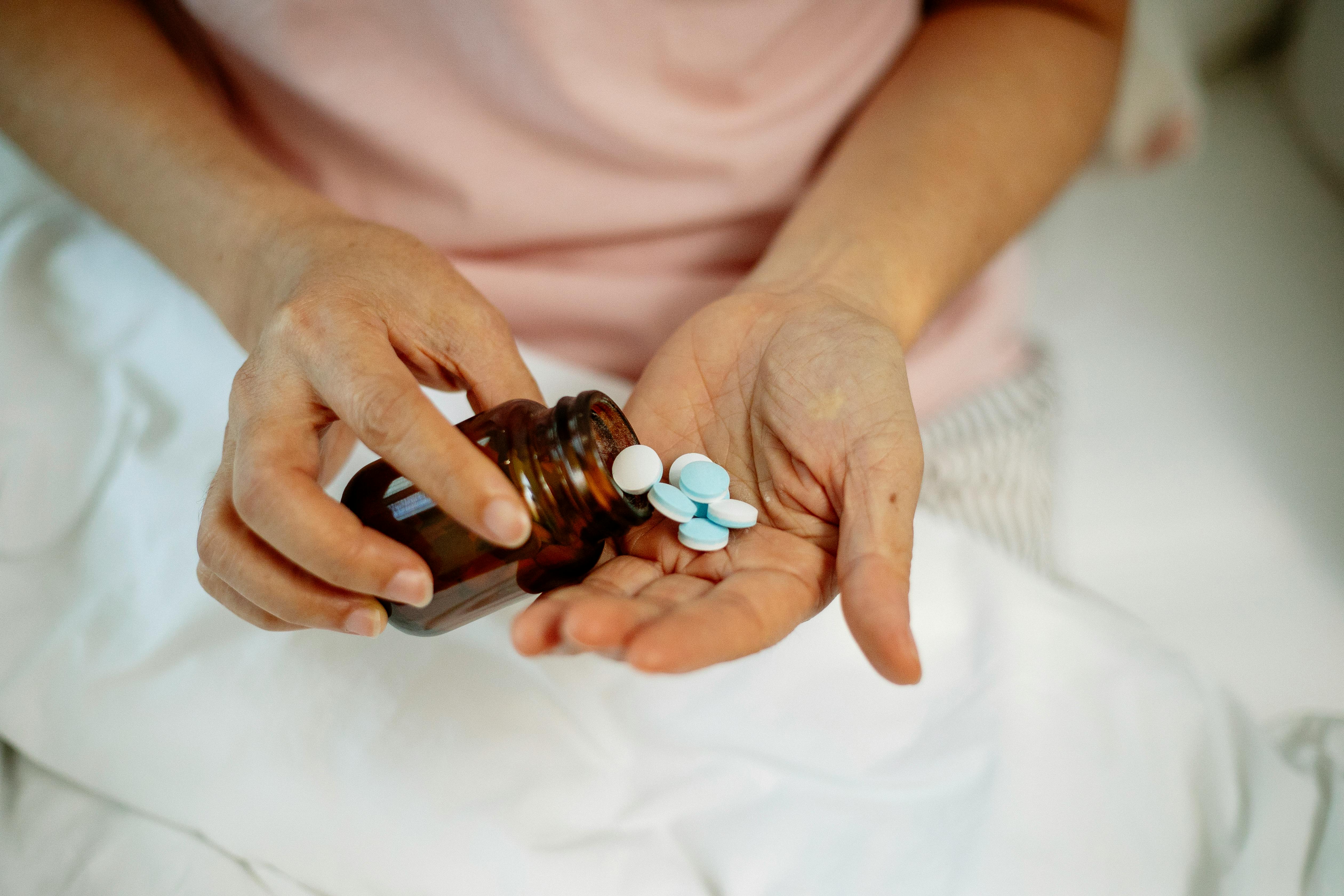 Woman taking pills from a jar on hand