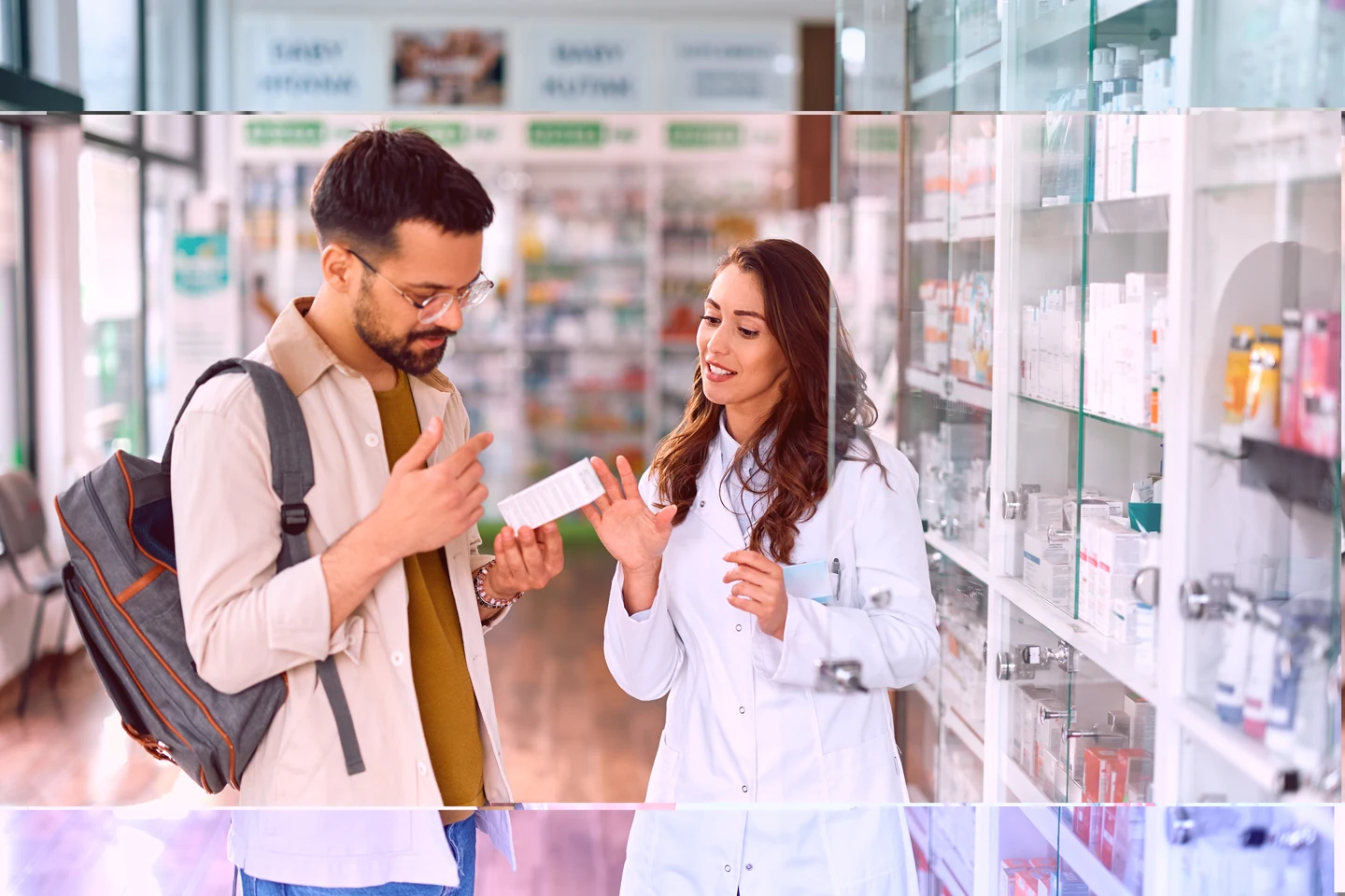 A pharmacist showing a box of medication to a customer in a pharmacy.